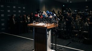 A row of news microphones at an empty press conference podium.