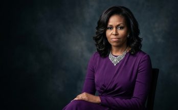 A formal, elegant portrait of former First Lady Michelle Obama in a purple dress.